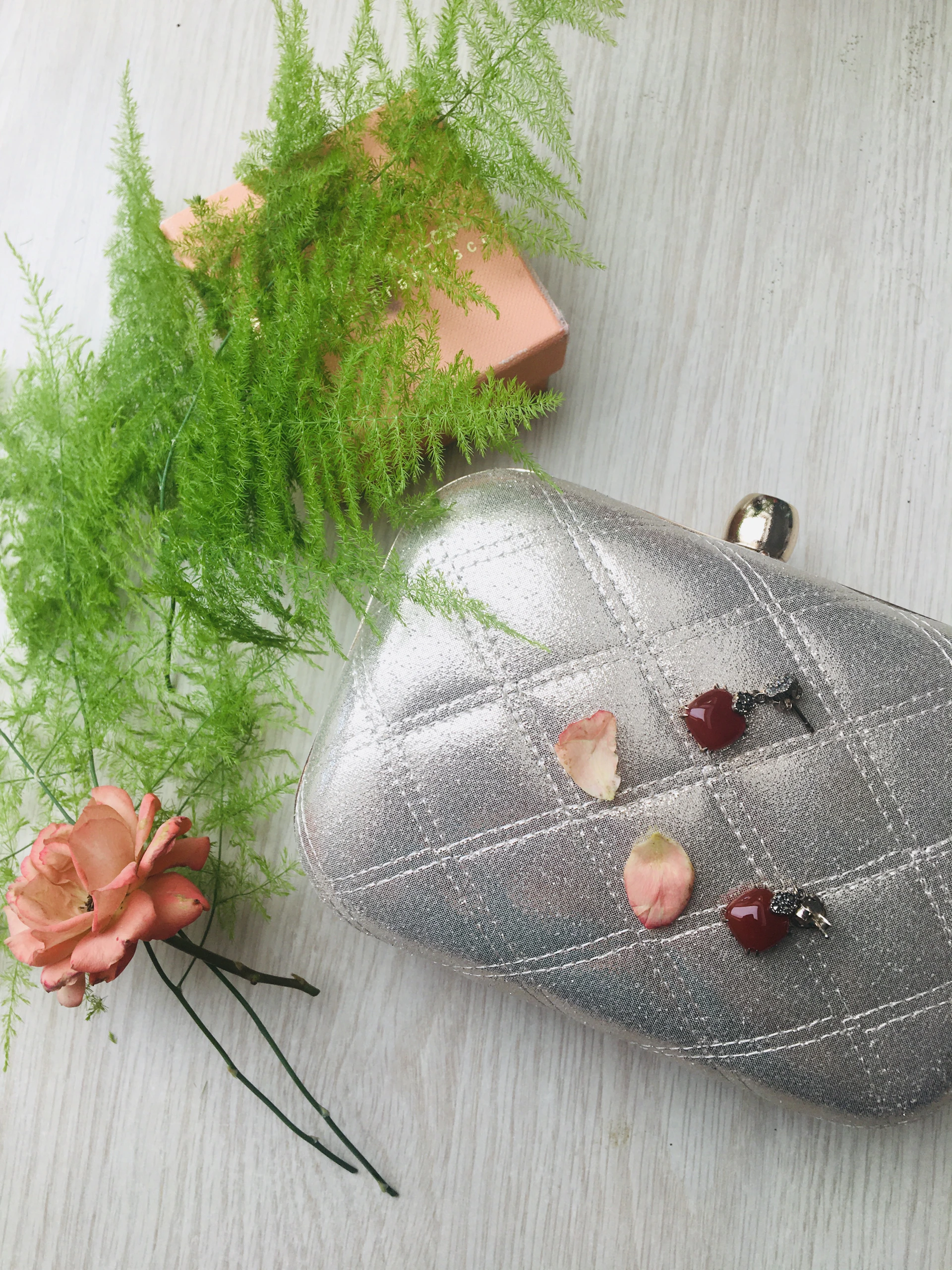 A luxurious deep burgundy clutch with intricate stitching placed on a polished wooden surface.