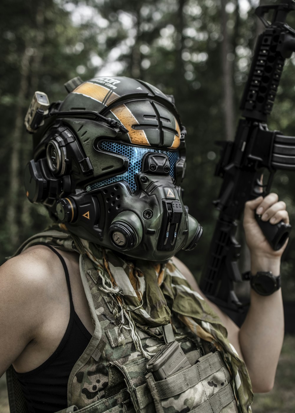 Frau in schwarz-braunem Camouflage-Tanktop mit schwarzem Gewehr
