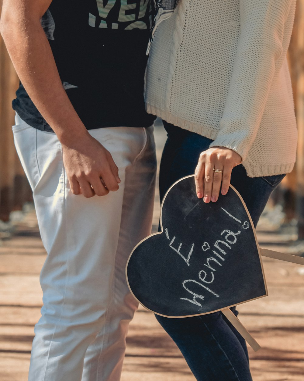 woman in white knit sweater and white pants holding black and white love print bag