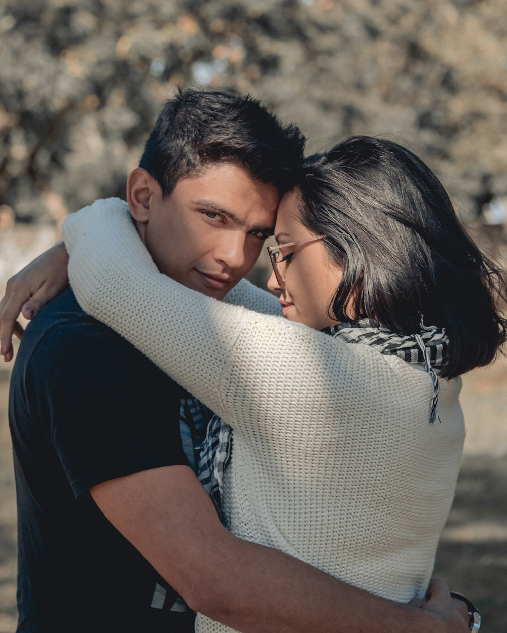 man in blue t-shirt hugging woman in white knit sweater