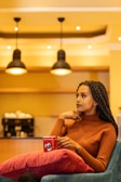 An artistic shot of a woman laughing in a cozy café.