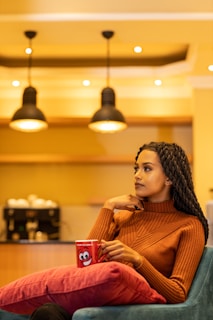 A woman smiling while looking at a map in a cozy terracotta-toned café.