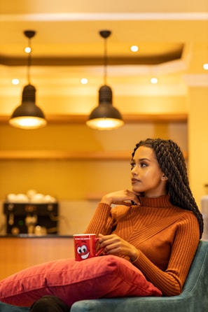 A smiling woman in casual attire sitting at a cozy café table.