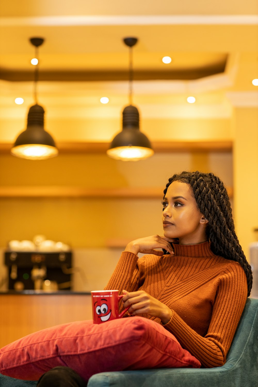 woman in brown and white striped long sleeve shirt holding red and white ceramic mug