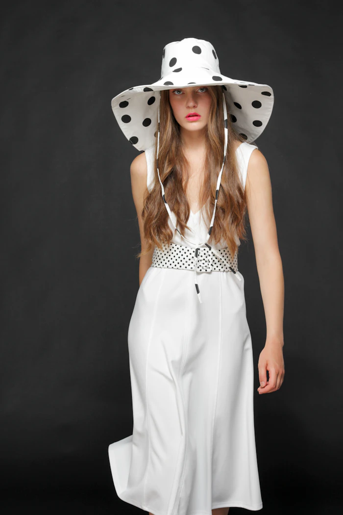 Woman in a white and black polka dot sleeveless dress
