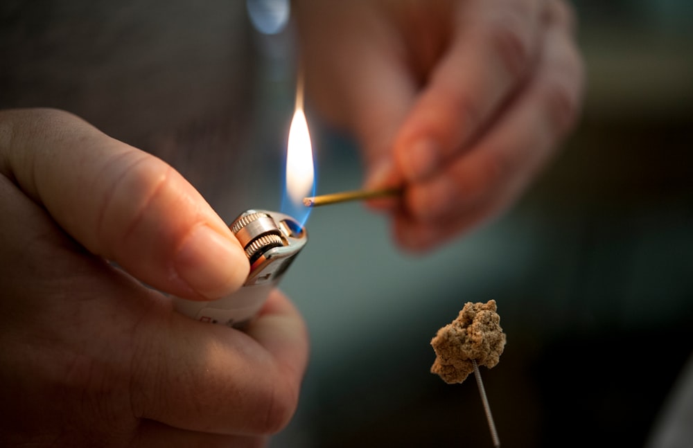 person holding lighted lighter with fire