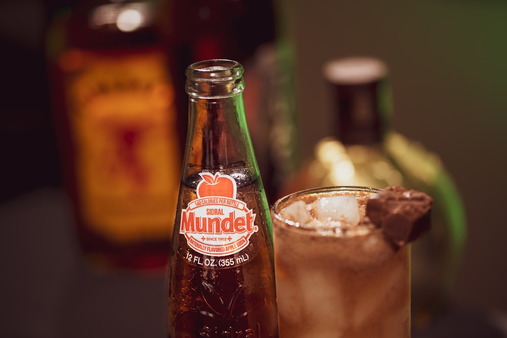 coca cola glass bottle beside clear drinking glass