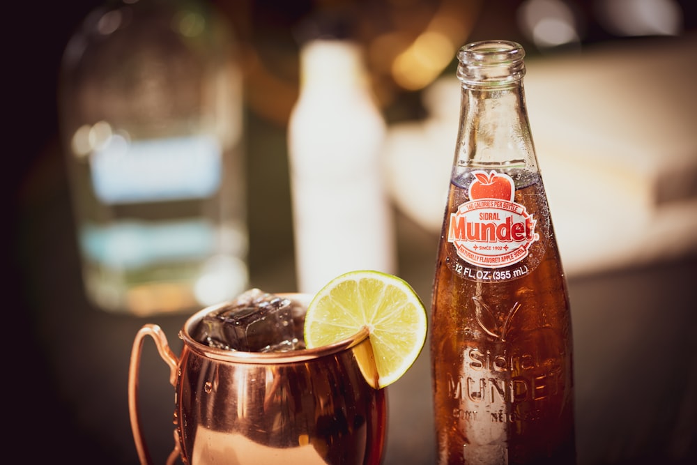 clear glass bottle with brown liquid and lemon