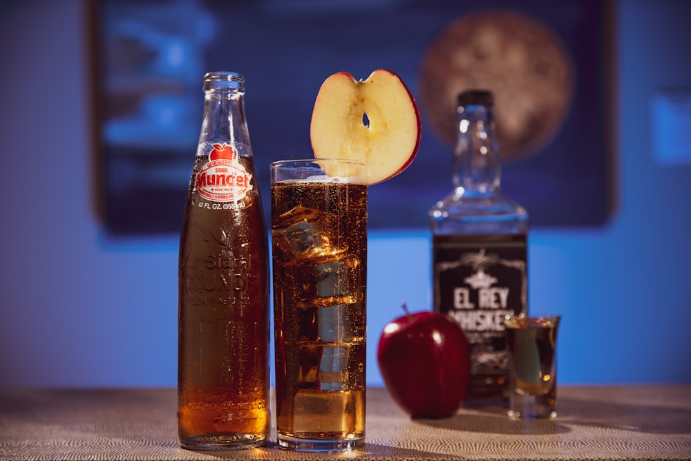garrafa de vidro transparente ao lado da fruta da maçã vermelha