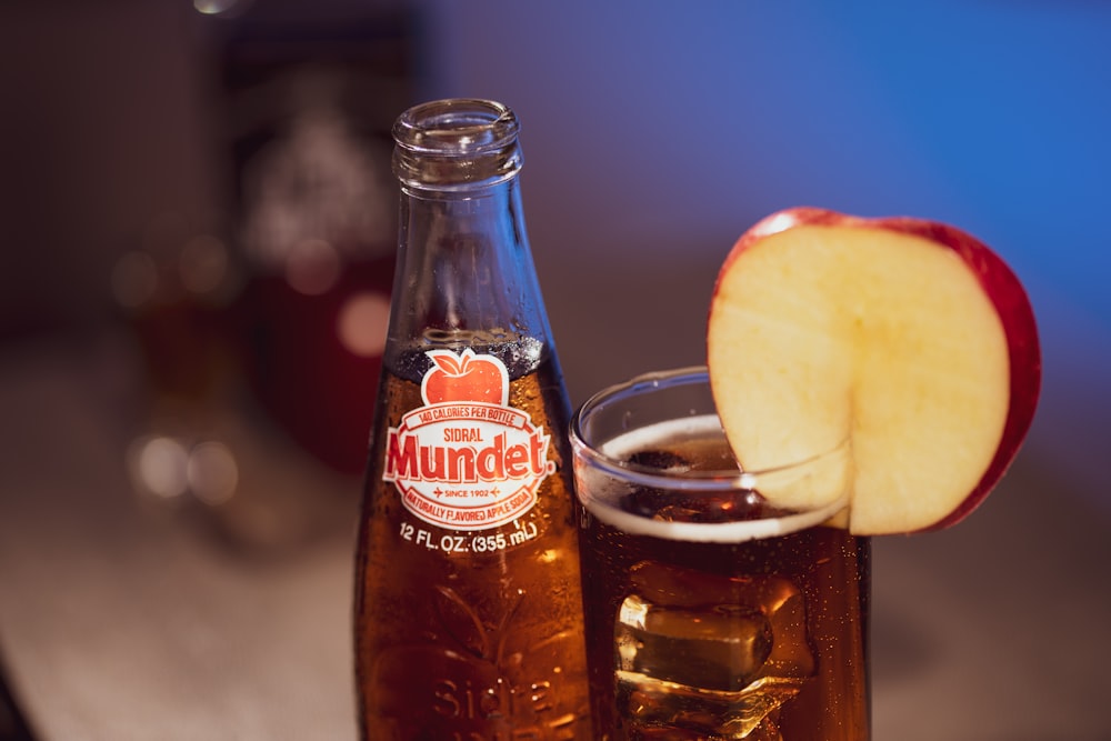 coca cola bottle beside clear drinking glass with ice