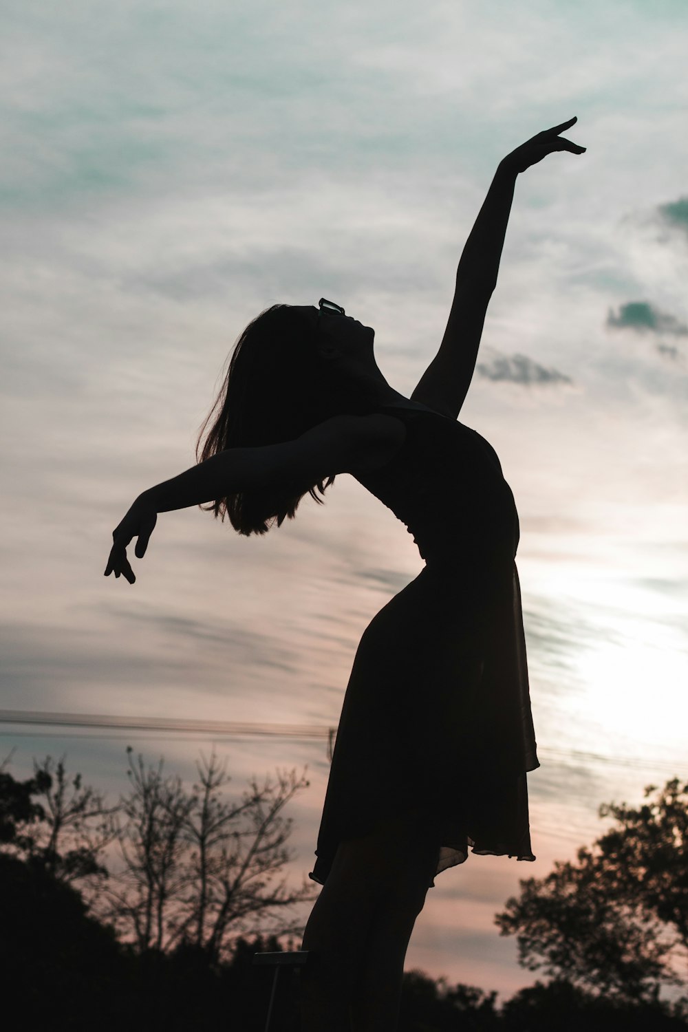 silhouette of woman raising her hands