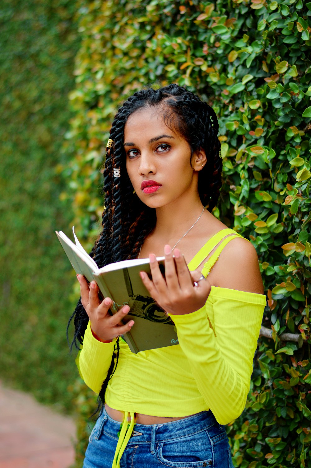 woman in yellow tank top holding book