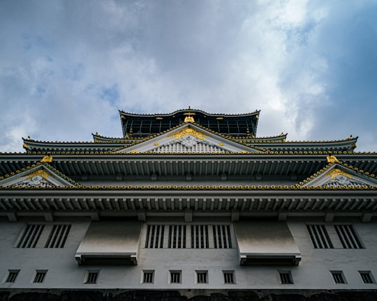 white and black concrete building under white clouds during daytime in Osaka Castle Park Japan