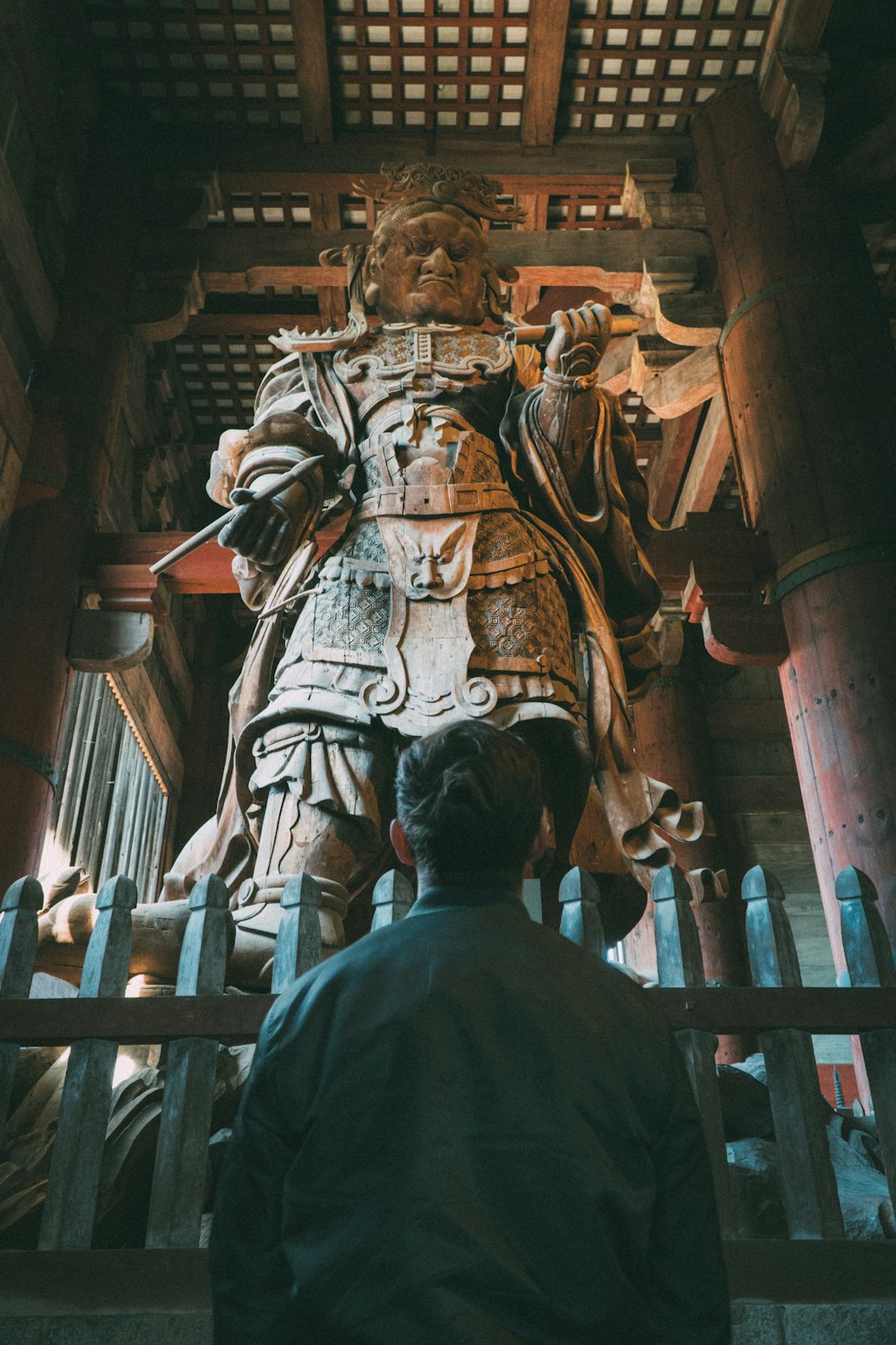 man in black shirt standing in front of brown concrete statue