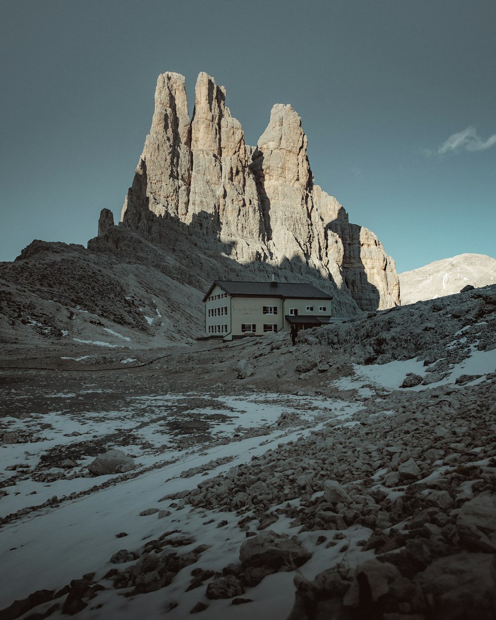 white and brown house near brown rocky mountain under blue sky during daytime