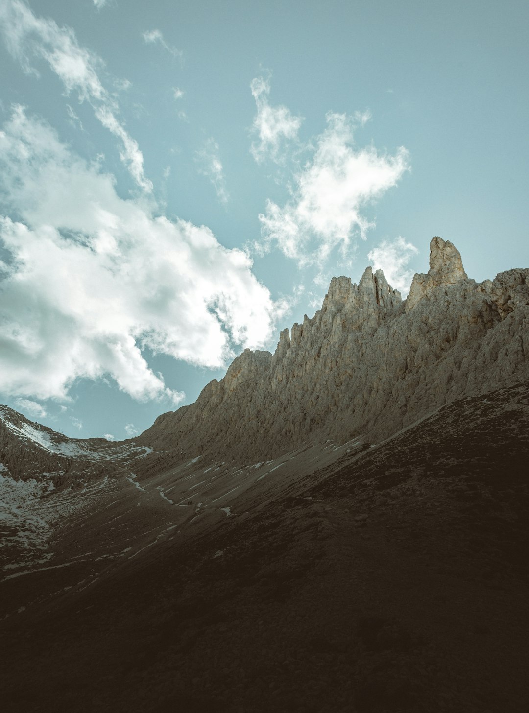 brown rocky mountain under white clouds and blue sky during daytime