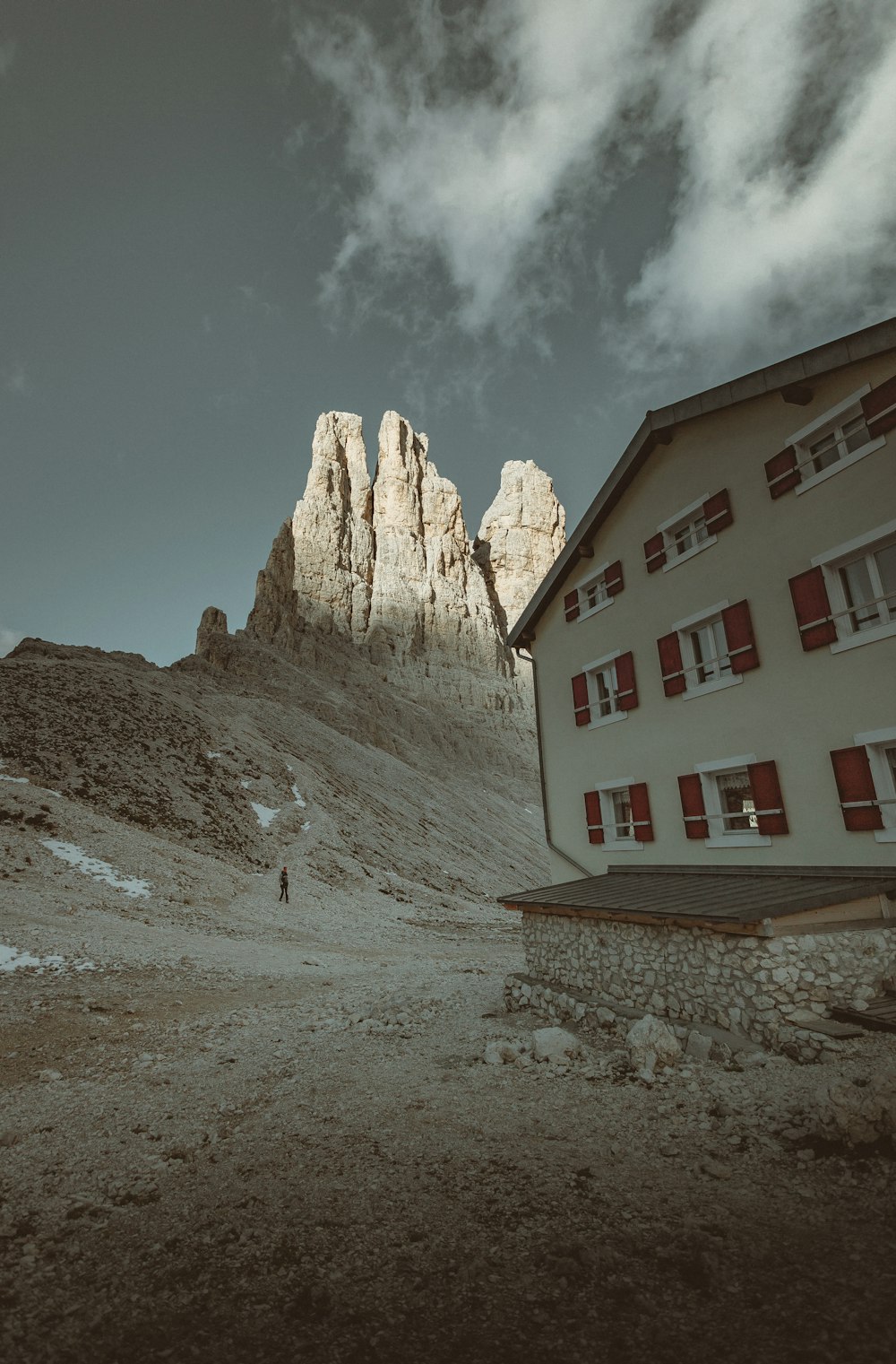 white and brown concrete house near brown rocky mountain under blue sky during daytime