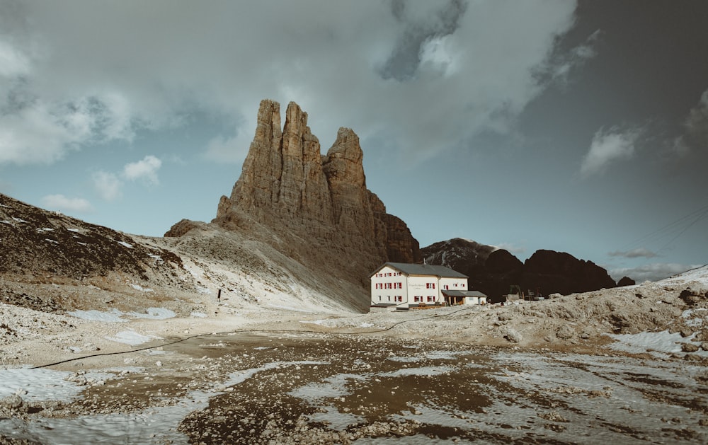 Casa blanca y roja cerca de la montaña rocosa marrón bajo el cielo azul durante el día