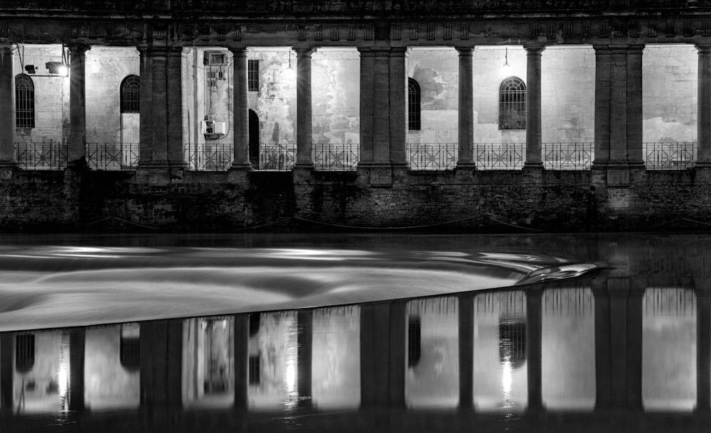 a black and white photo of a building reflecting in water