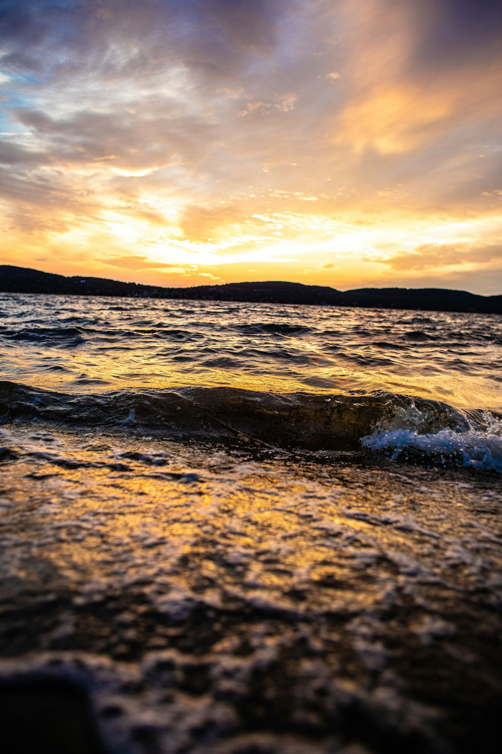 ocean waves crashing on shore during sunset