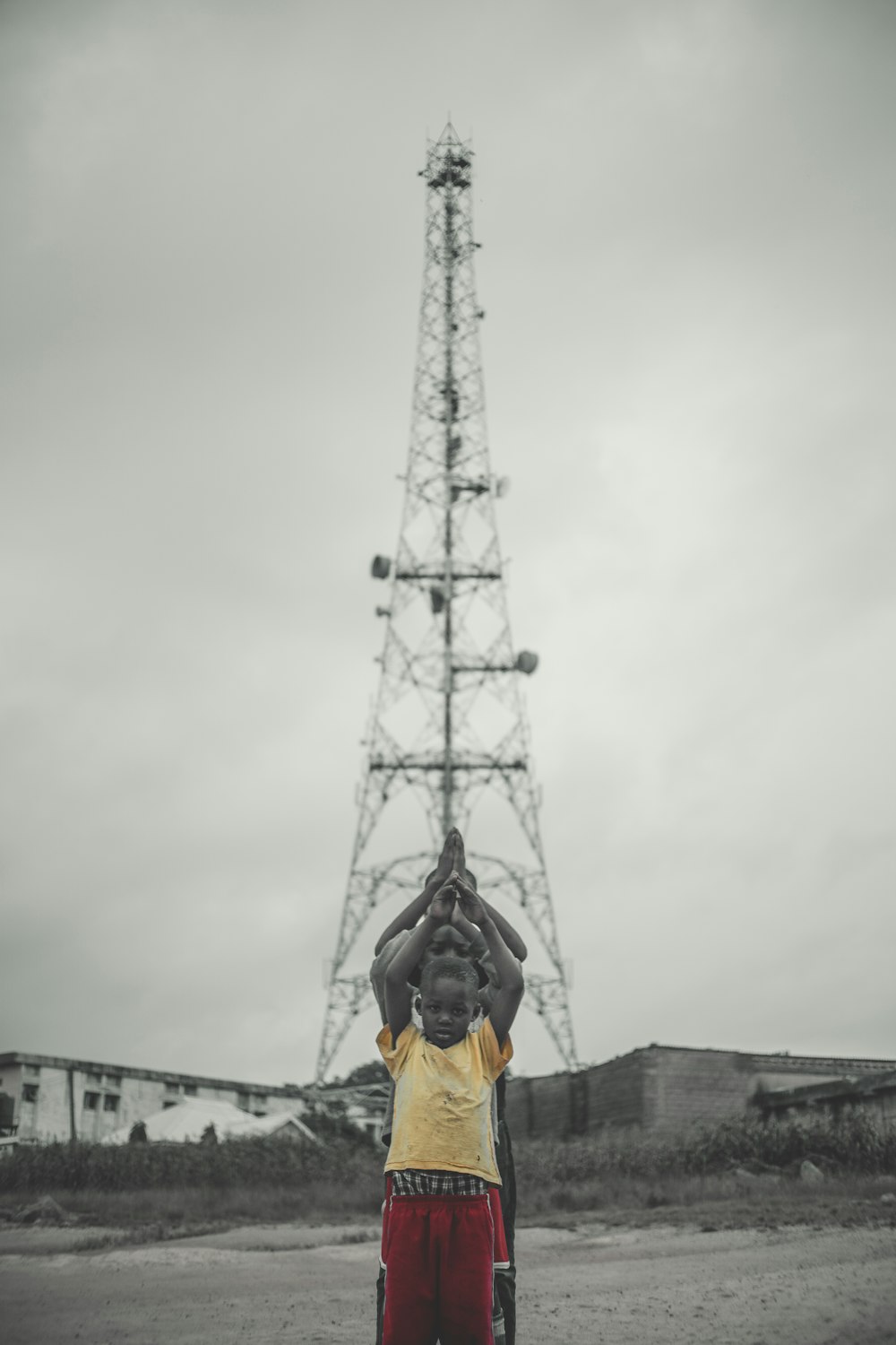 man in yellow jacket and black pants standing near white tower during daytime