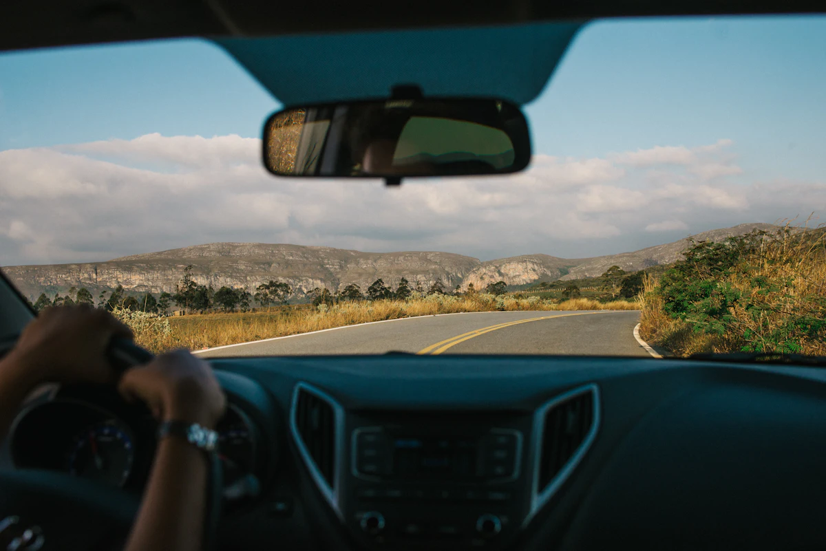 Driver's view of a curving two-lane road through dry hills