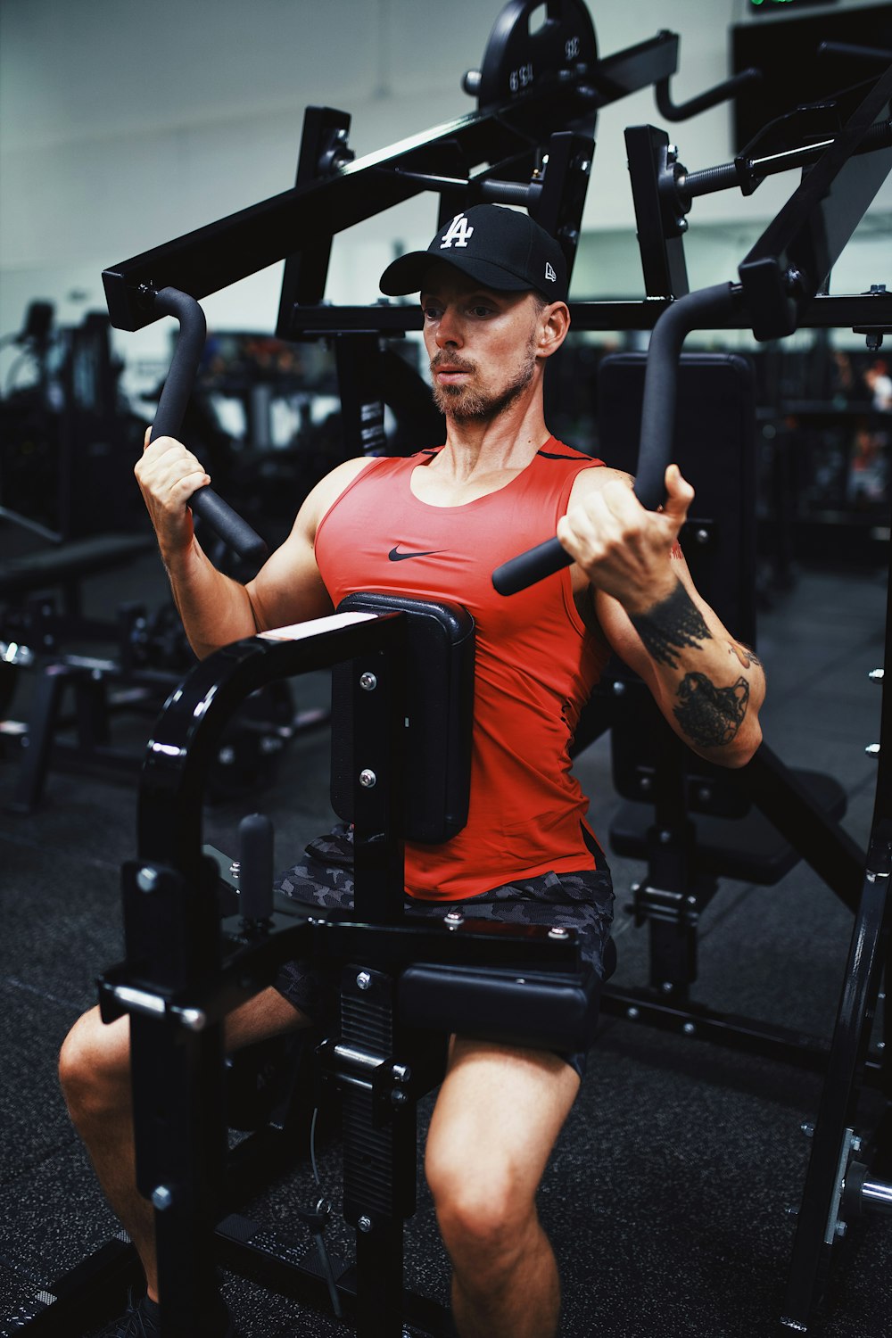 man in orange crew neck t-shirt and black fitted cap sitting on black stationary bike