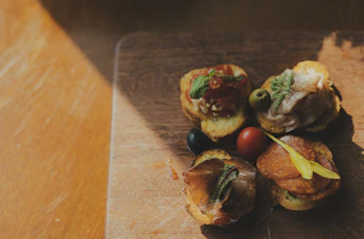 A warm, rustic wooden board displaying an assortment of antipasti including bruschetta, prosciutto, and olives under soft candlelight.