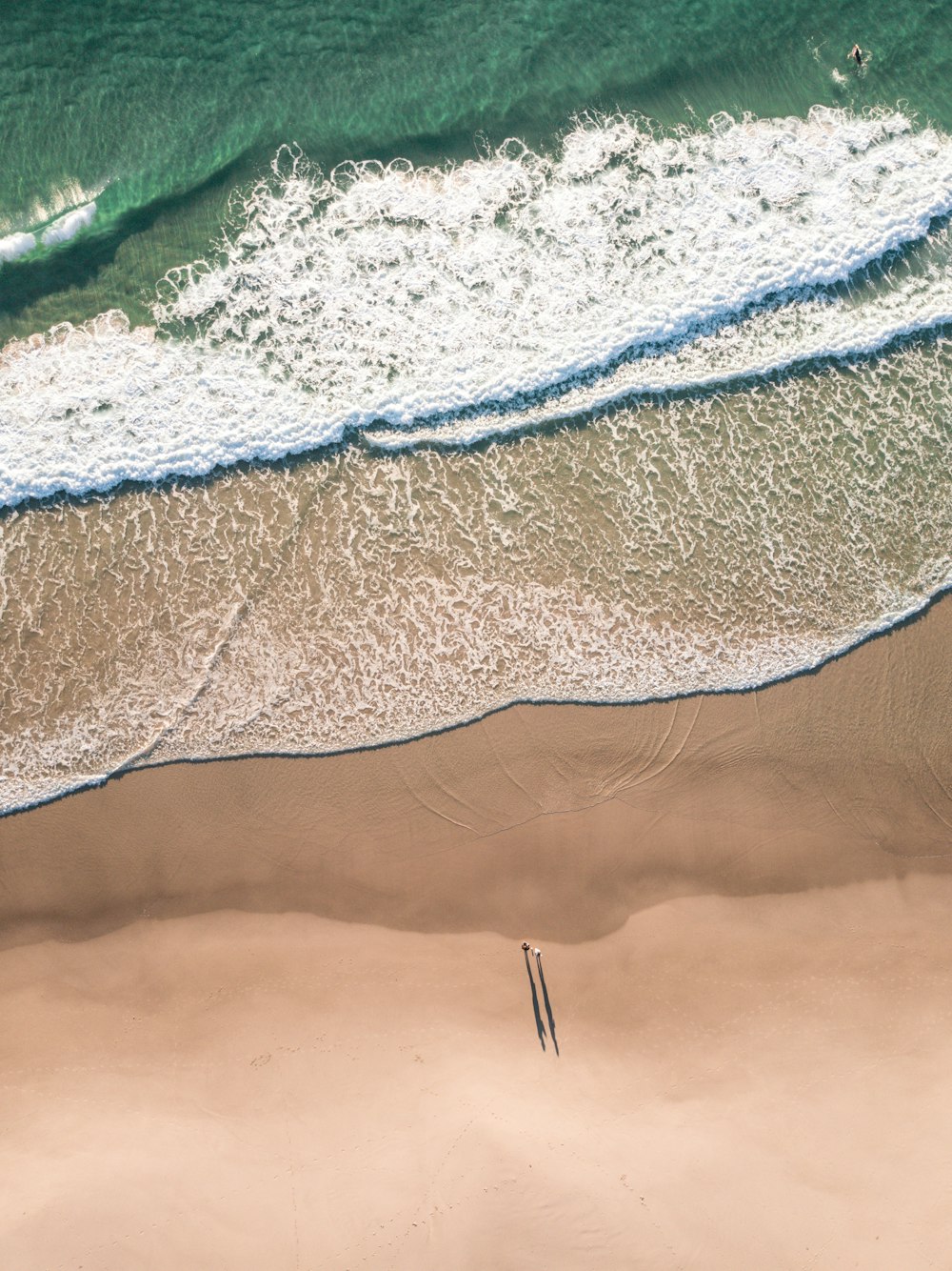 person in black shirt and blue denim jeans standing on brown sand beach during daytime