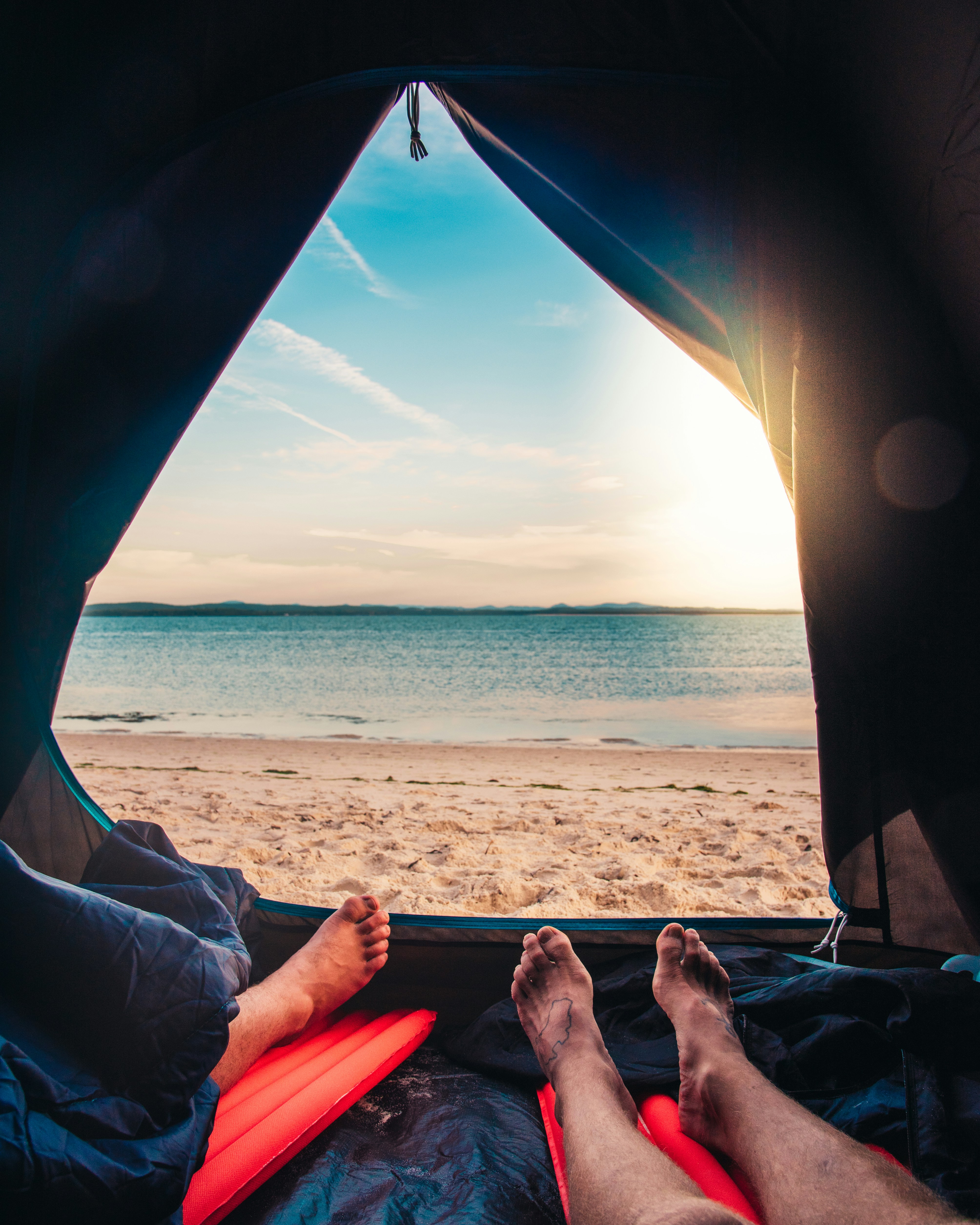 person lying on red and blue hammock near sea during daytime