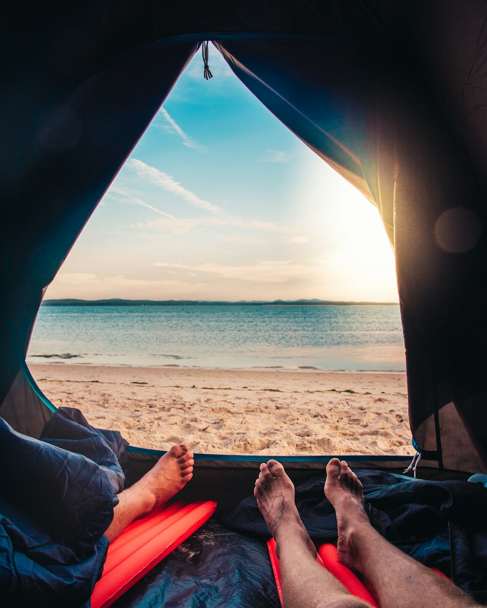 person lying on red and blue hammock near sea during daytime