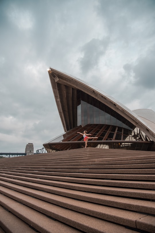 brown and white concrete building under white clouds during daytime in Sydney Opera House Australia