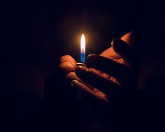 person holding lighted candle in dark room