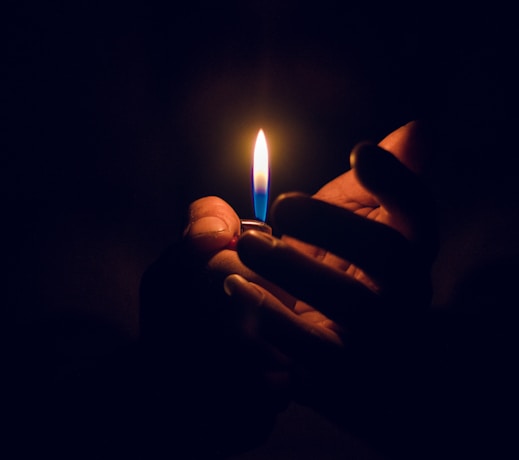 person holding lighted candle in dark room