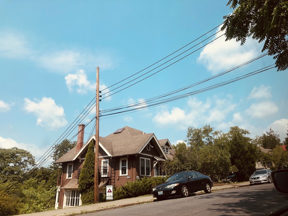 black car parked beside brown house