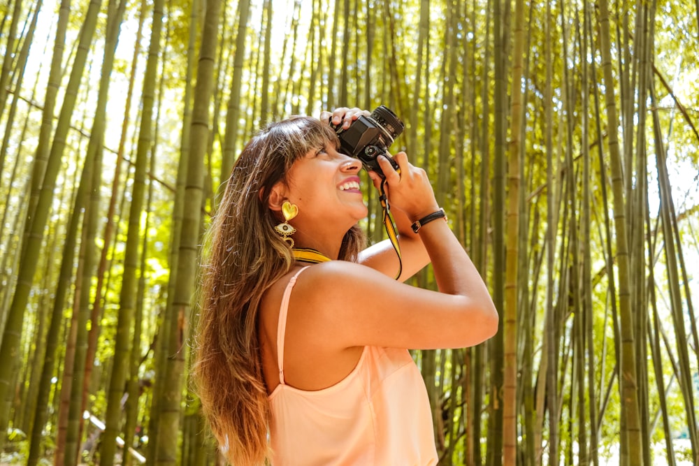 woman in yellow tank top holding black dslr camera