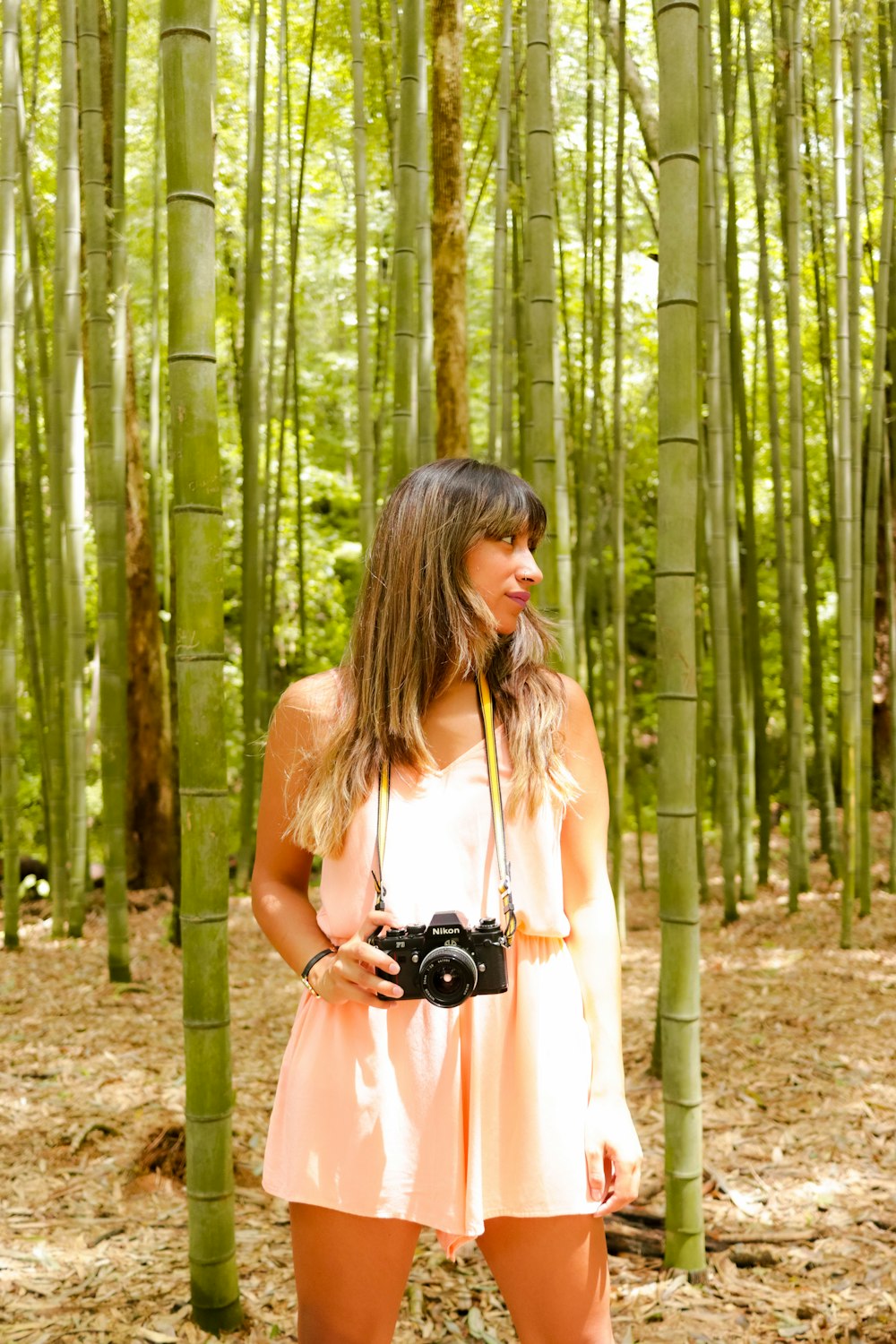 woman in white tank top holding black dslr camera