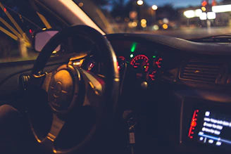 Close-up of a sleek mach1 performance car's dashboard glowing under city lights at dusk.