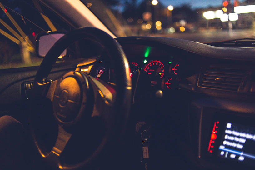 Close-up of a sleek mach1 performance car's dashboard glowing under city lights at dusk.