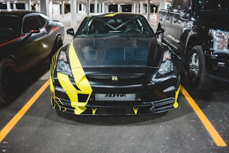 A sleek black car with yellow accents being serviced in a modern garage.
