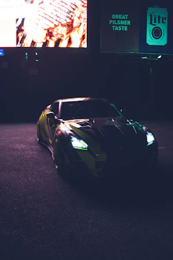 A sleek sports car parked under city lights with an influencer filming content nearby.