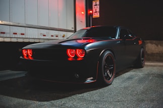 A sleek black and silver tow truck parked with flashing lights at dusk.
