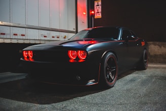 A sleek vehicle being carefully loaded onto a transport truck under moody lighting.
