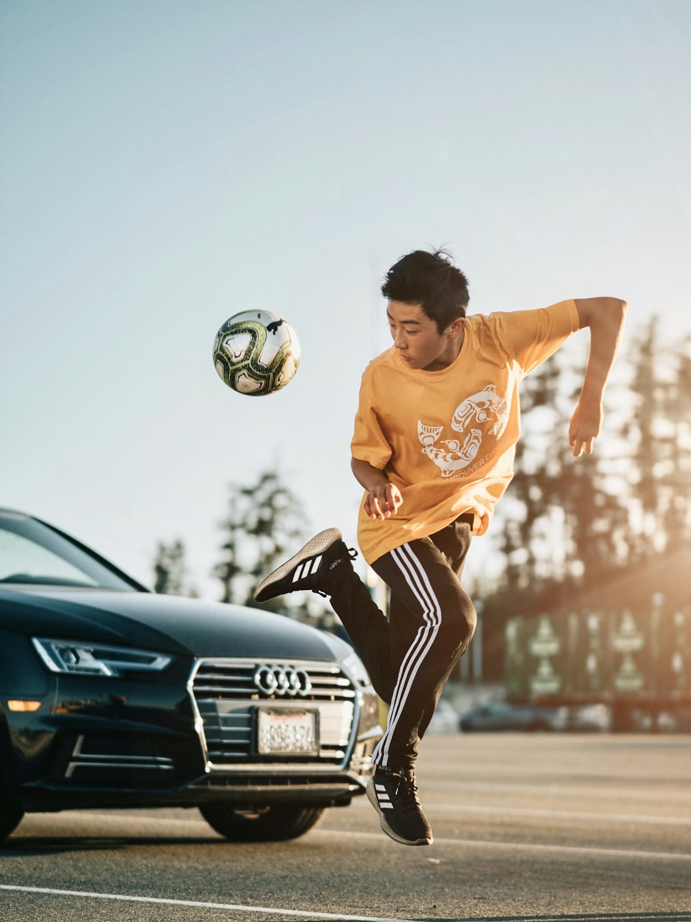 man in orange crew neck t-shirt and black shorts playing soccer during daytime