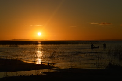 Sunset over the Amazon River with canoes gently floating near the shore.