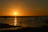 A serene sunset over the mangroves with a traditional pirogue gliding through calm waters.