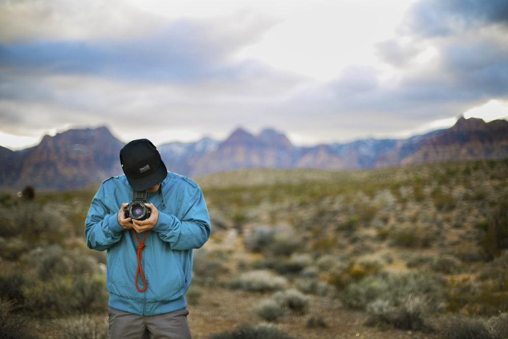 man in green hoodie holding black dslr camera