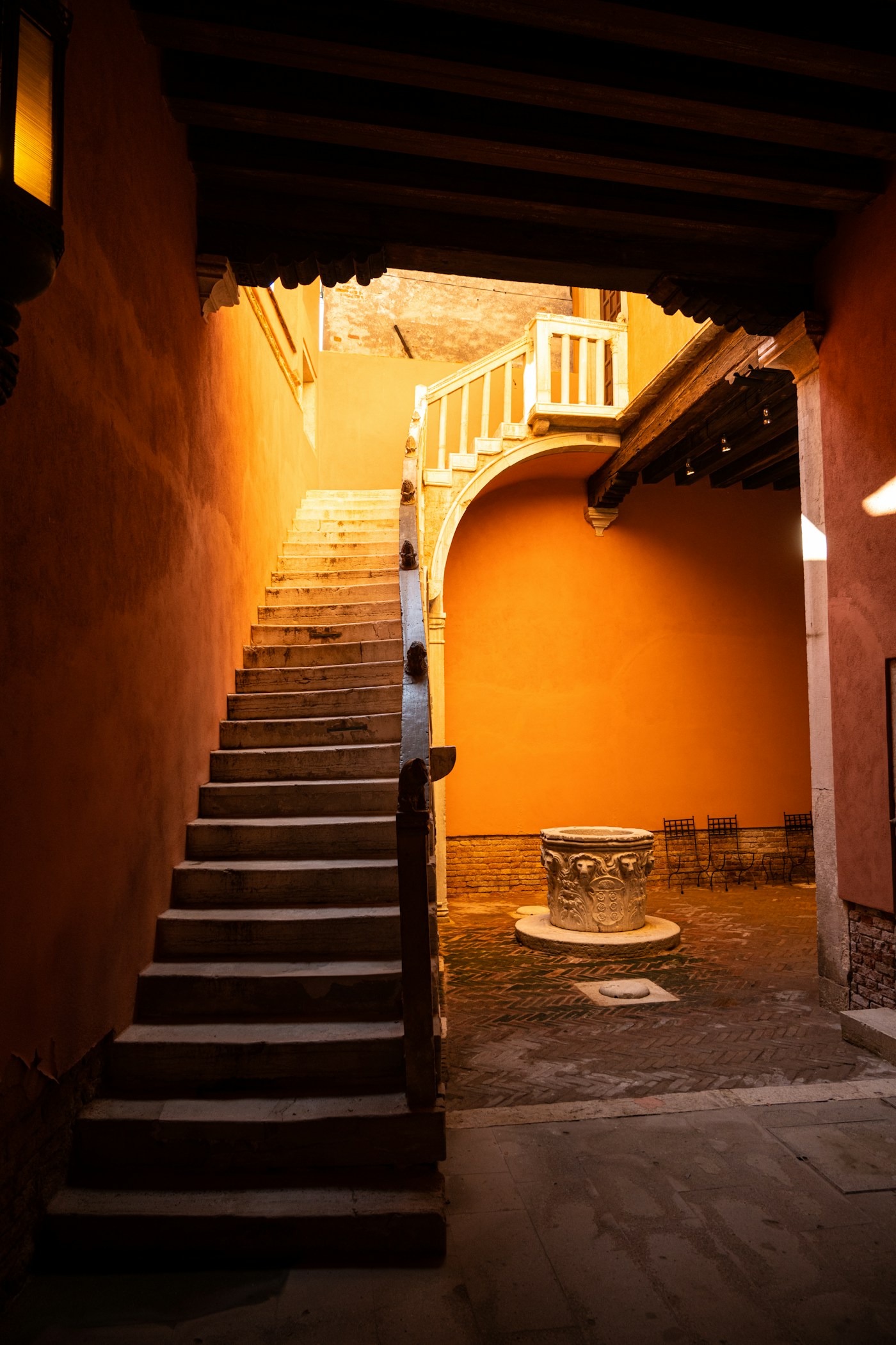 Sunlit orange walls and a curved stone staircase; illustrative architectural photography.