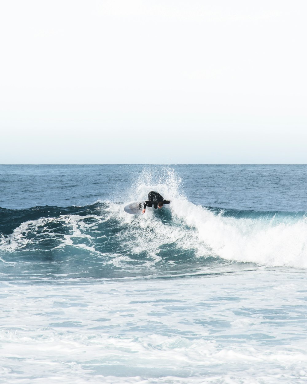 昼間、海の波でサーフィンをする男
