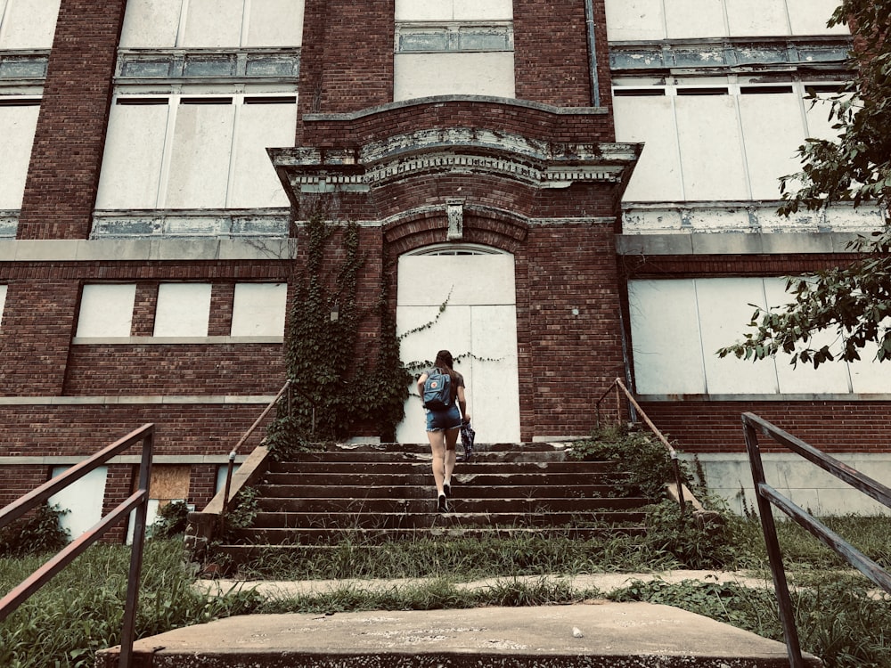 woman in black jacket and blue denim jeans standing on brown concrete stairs